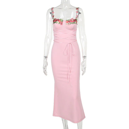 A pink sleeveless knee-length dress with floral decal accents at the chest and waist girdling feature.