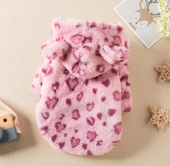 A pink pet clothes with a heart pattern displayed on a surface, likely made of fleece fabric.