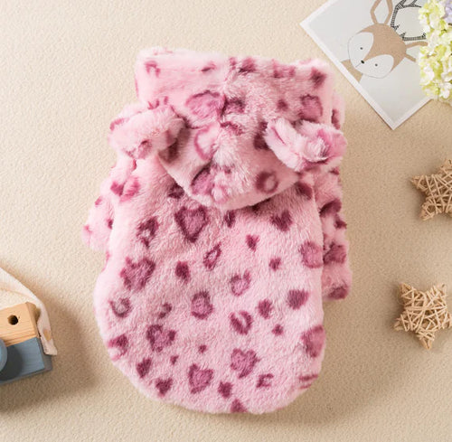A pink pet clothes with a heart pattern displayed on a surface, likely made of fleece fabric.