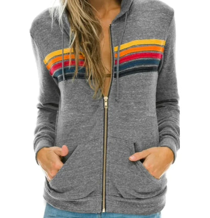 A woman wearing a black zip-up hoodie with vibrant multicolor stripes on the front.