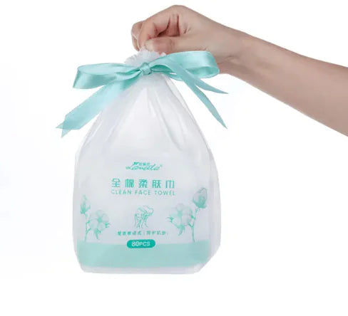 Bag of clean face towels with a blue ribbon being held by a hand on a white background.