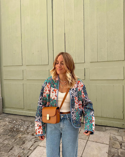 A person wearing a red and brown retro printed collar jacket over a white top, paired with a beige handbag.