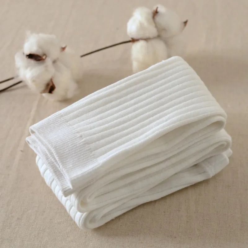 A pair of brown cotton leggings folded and placed on a flat surface with cotton flowers in the background.