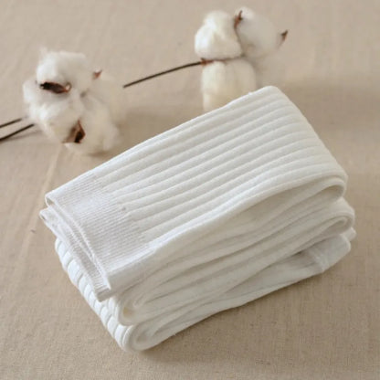 A pair of brown cotton leggings folded and placed on a flat surface with cotton flowers in the background.