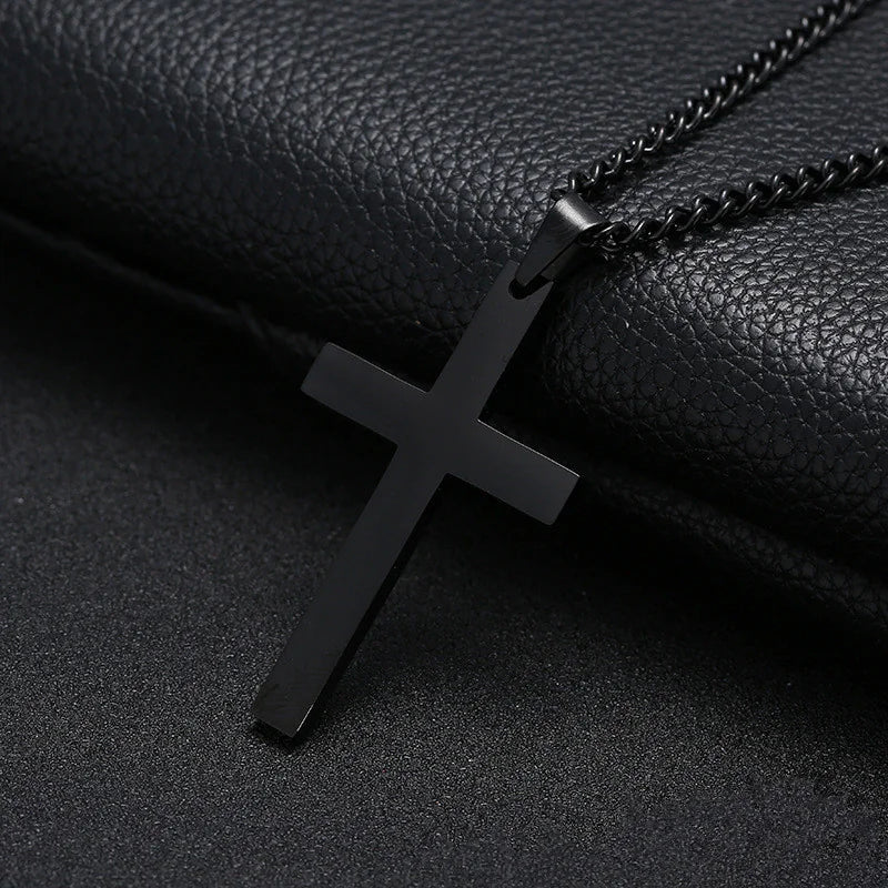 A black cross necklace made of stainless steel, displayed against a black leather background.