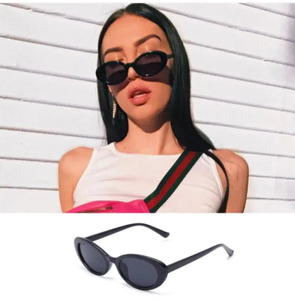 A woman with long dark hair wears Retro Oval Sunglasses, a white sleeveless top, and a crossbody strap as she stands against a white textured wall. Below her is a close-up of the Retro Oval Sunglasses.