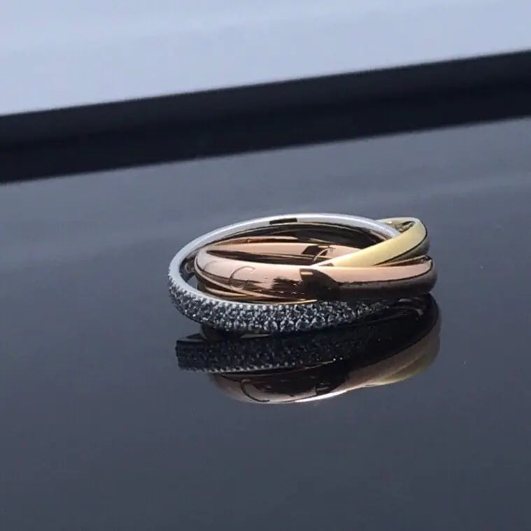 A set of three rings featuring a couple design with diamond accents, displayed on a reflective surface.