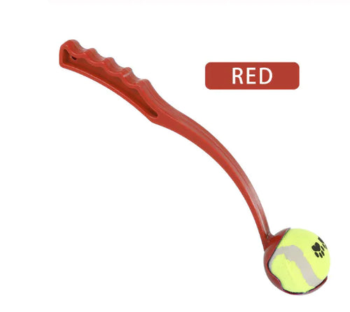 A red dog ball launcher with an ergonomic handle, designed to throw a tennis ball for fetch.