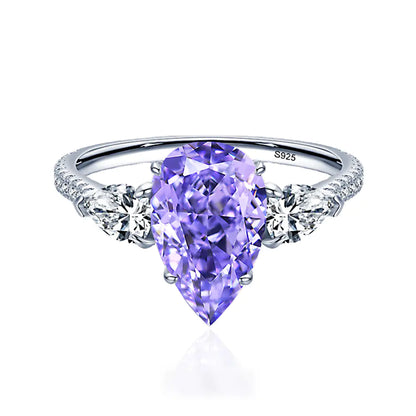 A sterling silver ring with a drop-shaped purple diamond centerpiece and accent diamonds around it.