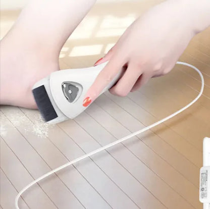A person is using an electric pedicure device to remove calluses from their foot, which is placed on a wooden floor.