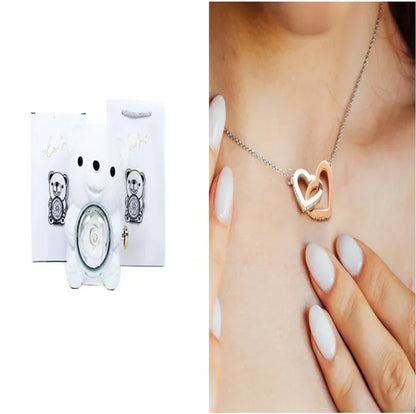 A teddy bear gift box in blue with a preserved rose and a necklace, alongside a rotating rose jewelry box, against a white background.