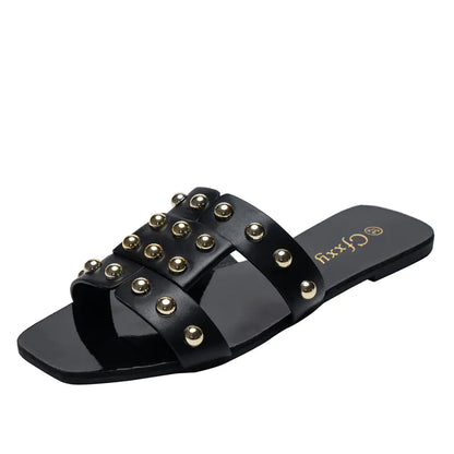A pair of brown flat sandals with metal rivet accents on a black rubber sole, designed for women's casual wear.