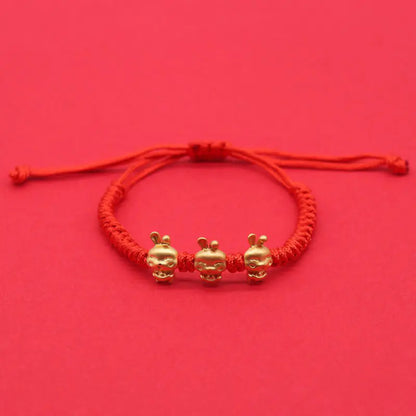 A simple woven hand rope bracelet with a floral shape and multicolored threads on a red background.