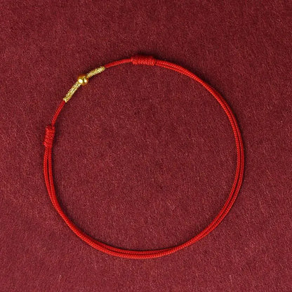 A simple woven hand rope bracelet with a floral shape and multicolored threads on a red background.