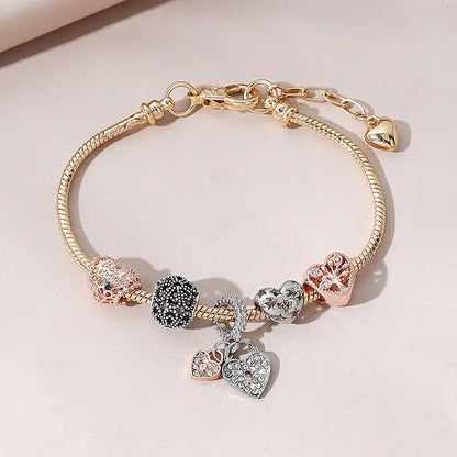 A gold-colored bracelet featuring a heart-shaped design with multiple charms including a heart and a tree, adorned with artificial gemstones.