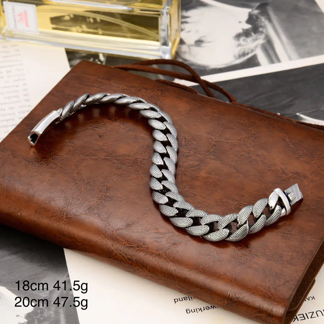 A silver fashion bracelet with a glossy snake pattern, displayed on a brown leather surface.