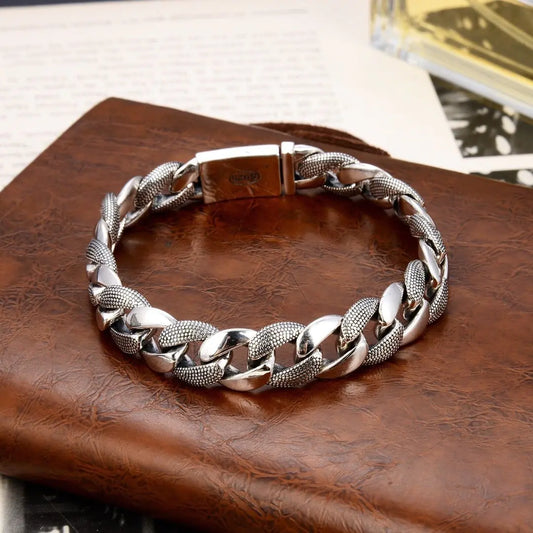 A silver fashion bracelet with a glossy snake pattern, displayed on a brown leather surface.