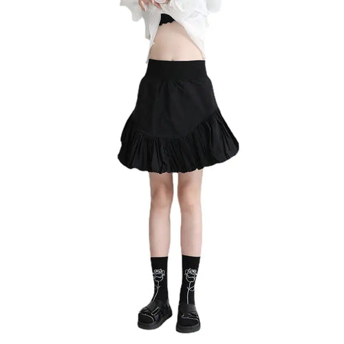 A person wearing a high-waisted, bubble hem skirt in black color, paired with a white top and black socks with a graphic design.
