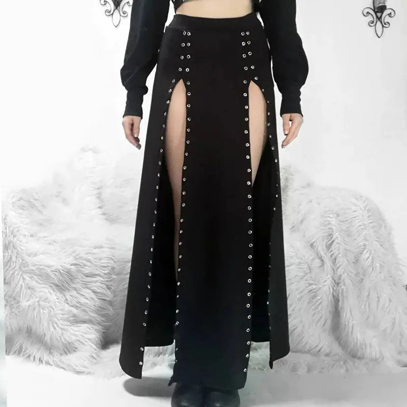 A high-waist mid-length black skirt with rivet and slit design, paired with a black top and displayed in front of a white furry background.