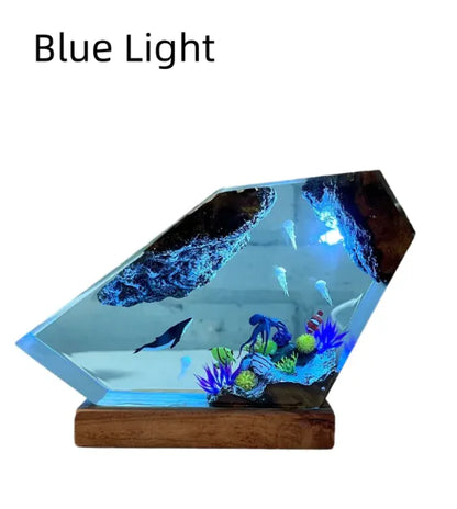 A resin night light featuring a blue lighted scene with a humpback whale and jellyfish, set on a wooden base.