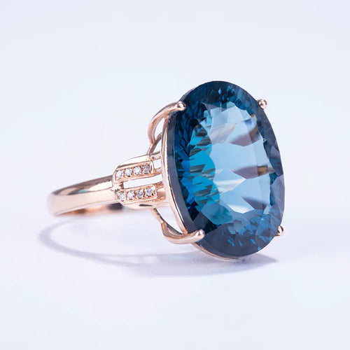 A blue synthetic sapphire ring with gold-colored metal and small diamond-like stones, designed for women.