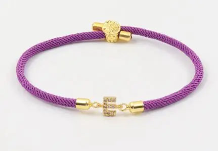 A dark green initial letter charm bracelet with a gold-colored clasp and a charm in the center.