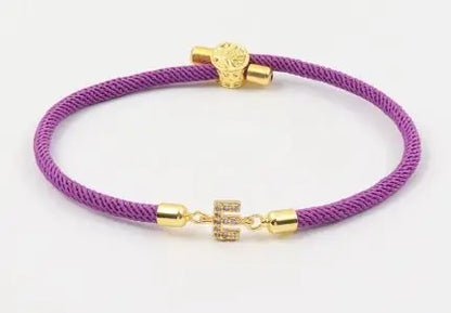 A dark green initial letter charm bracelet with a gold-colored clasp and a charm in the center.