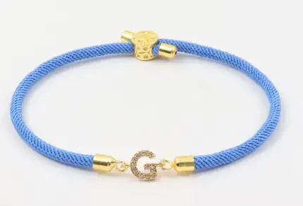 A dark green initial letter charm bracelet with a gold-colored clasp and a charm in the center.