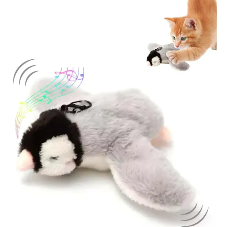 Interactive plush bird cat toy with a grey body, black and white head resembling a cat, and a small speaker device attached to its chest. The toy is shown in motion with a depiction of sound waves indicating it makes chirping sounds.