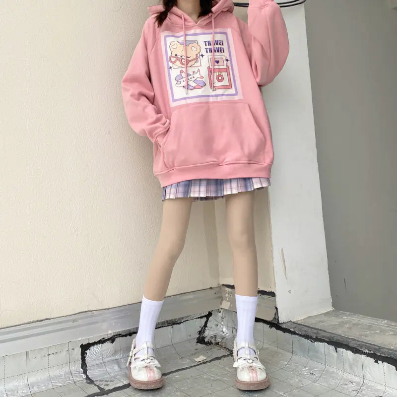 A woman wearing a white velvet sweater with a Japanese cartoon print, paired with a plaid skirt and white shoes.