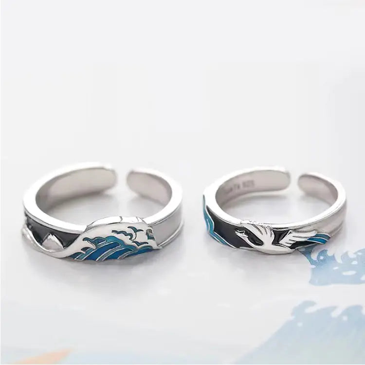 Two rings with a geometric design, one with blue accents and another with black accents, on a white background.