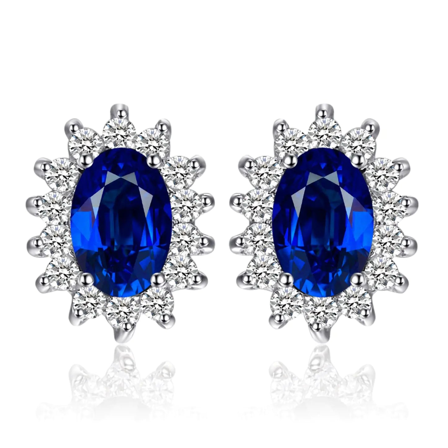 A pair of 14k gold plated 925 sterling silver stud earrings featuring blue sapphire gemstones surrounded by smaller clear crystals, designed in a princess diana or kate middleton style.