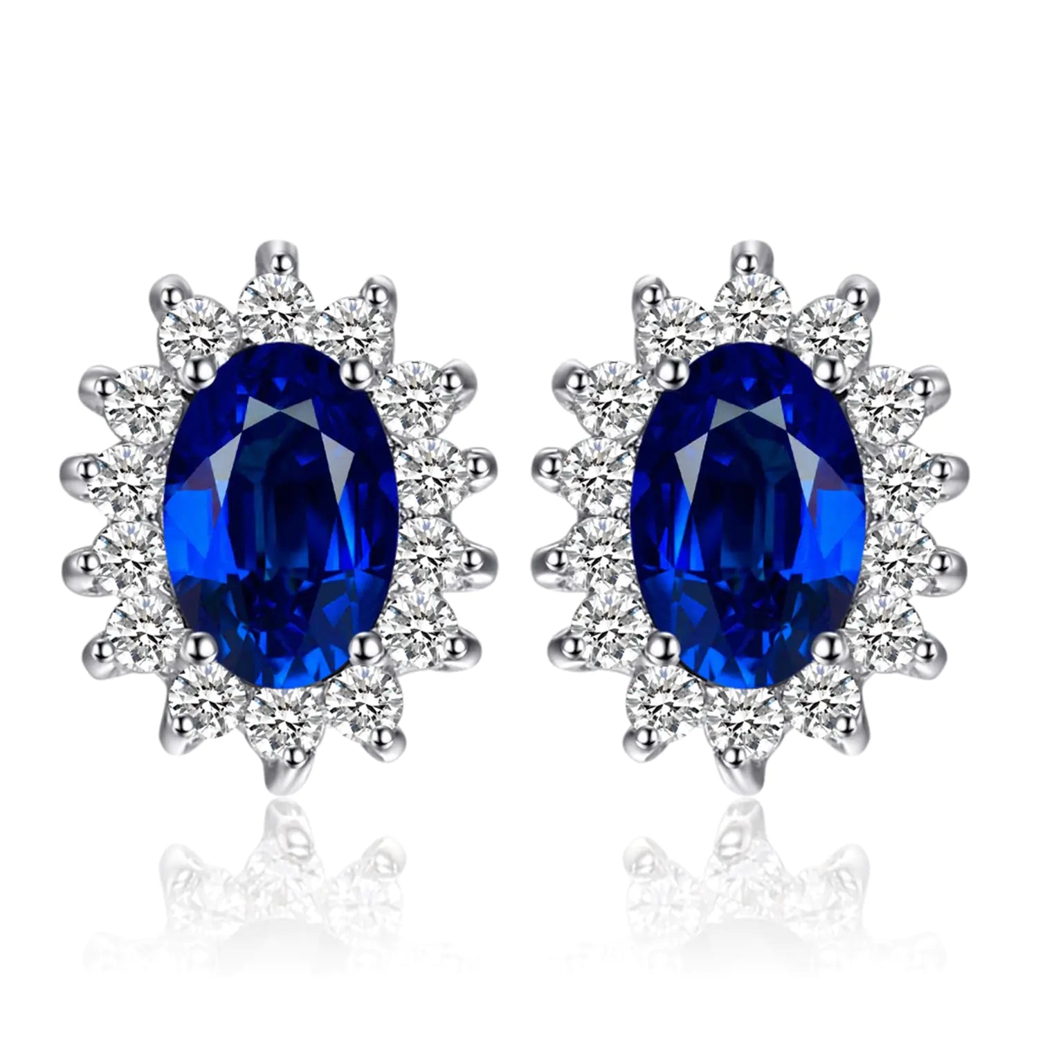 A pair of 14k gold plated 925 sterling silver stud earrings featuring blue sapphire gemstones surrounded by smaller clear crystals, designed in a princess diana or kate middleton style.
