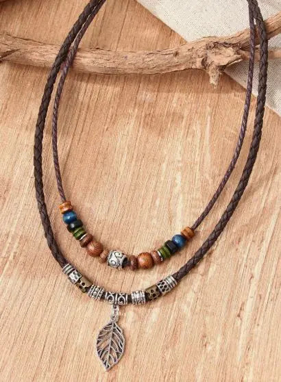 A necklace with a brown cord featuring a silver leaf pendant and colorful beaded decorations.