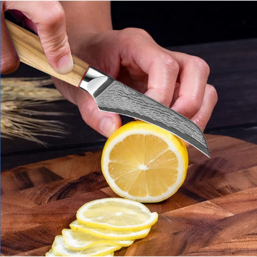 A hand using a knife to slice a lemon on a wooden cutting board.
