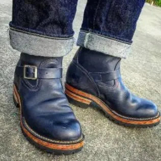 A pair of brown mid-tube flat-bottomed wedge boots with buckles and a pointed toe.