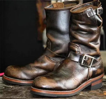 A pair of brown mid-tube flat-bottomed wedge boots with buckles and a pointed toe.