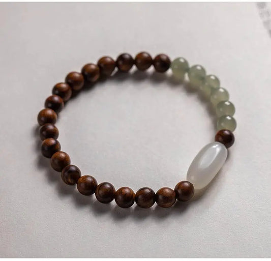 A two-tone bracelet with round beads, featuring nanmu hand string and Hetian jade, displayed against a light background.