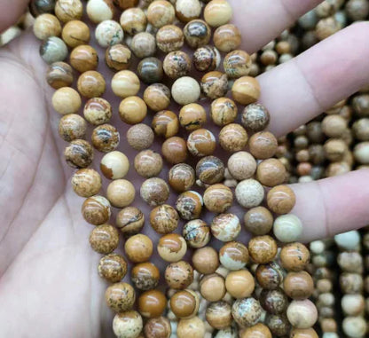 A hand holding round beads with a mix of blue and white colors, part of the Natural Tiger Stone Powder with Amethyst and Lapis collection.