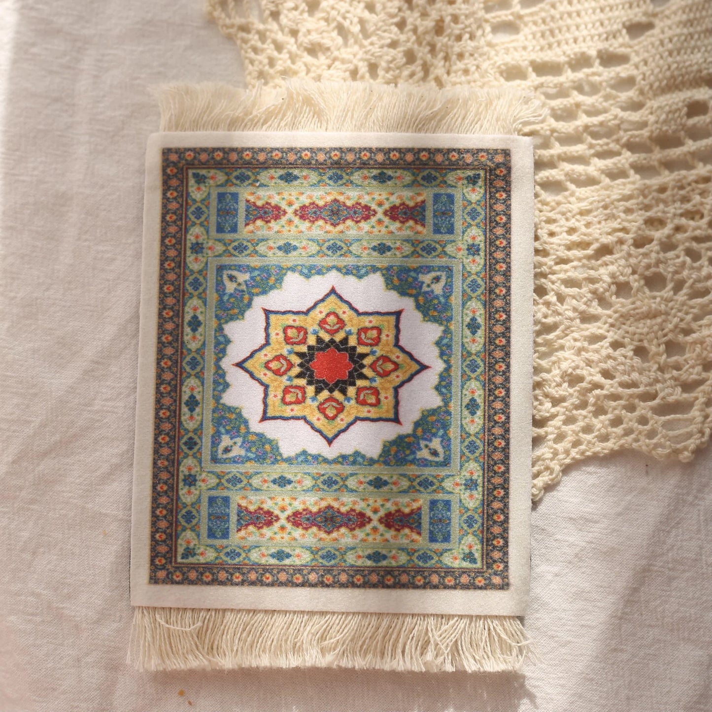 A rectangular mouse pad with a vintage Persian carpet design, featuring a prominent star shape in the center, placed on a textured white surface.
