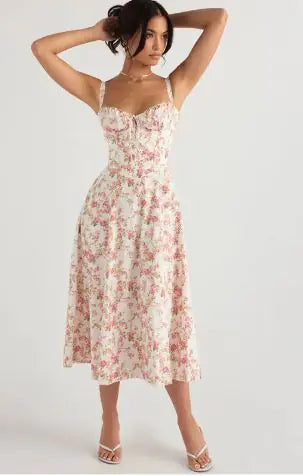 A woman modeling a sleeveless, high-waisted, floral print, A-line long skirt dress with straps.