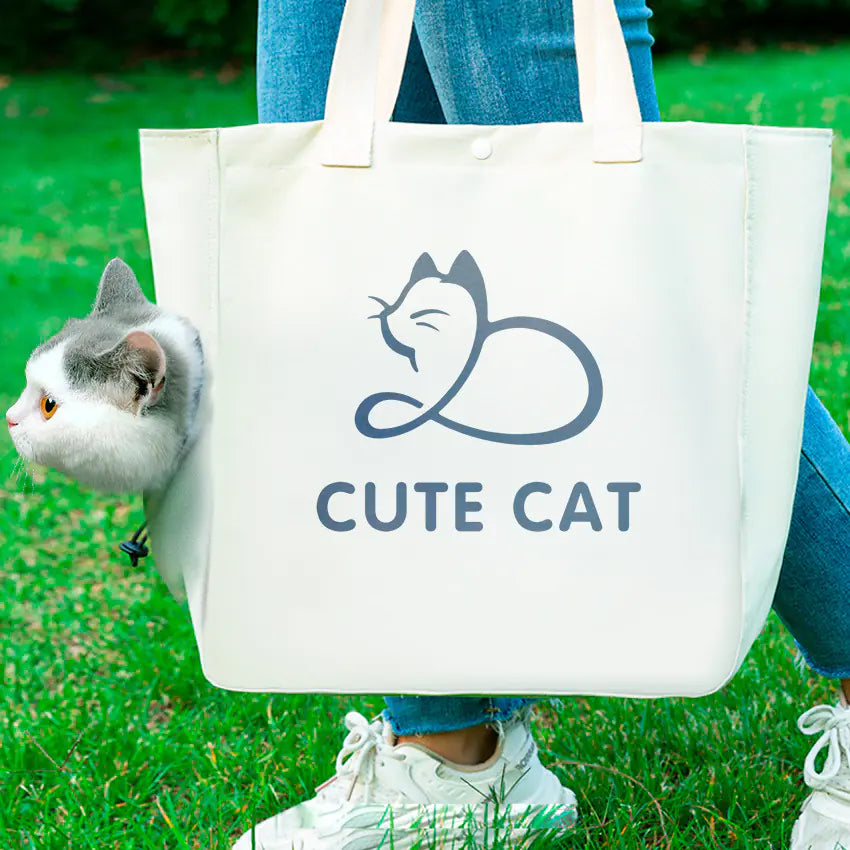 A white canvas handbag with a cute cat design and text 'CUTE CAT' is held by a person with a cat partially visible to the left of the frame.