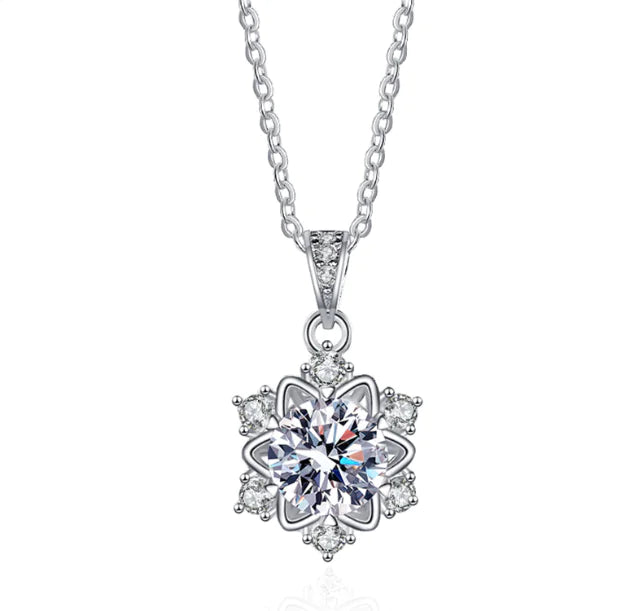 A sterling silver snowflake pendant necklace with a central moissanite or zircon crystal, surrounded by smaller clear crystals on a chain.