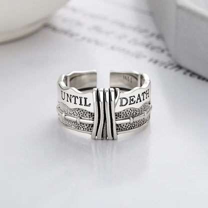 A silver ring with a distressed design and the text 'TIL DEATH' engraved on it, displayed against a light background.