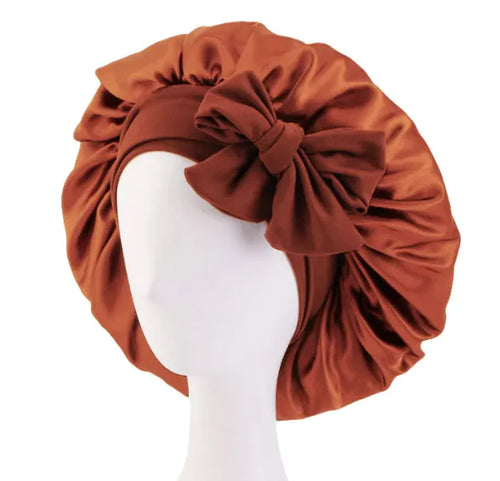 A brown silk ribbon round hat on a mannequin head.