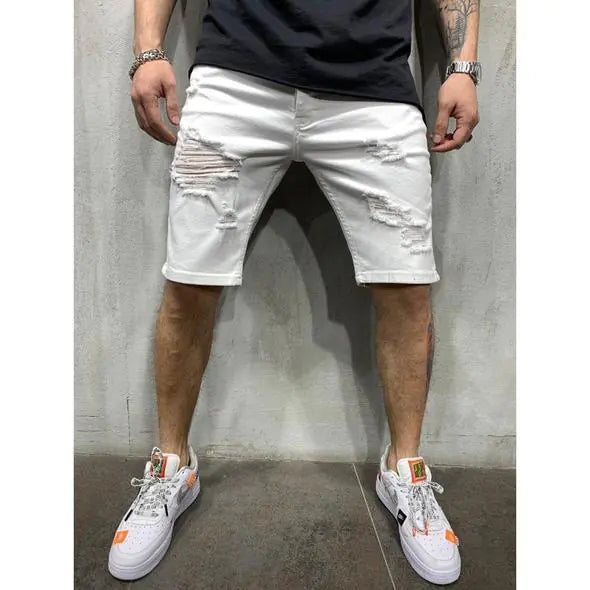 A pair of men's slim fit denim shorts with holes, worn with a black top and white sneakers.