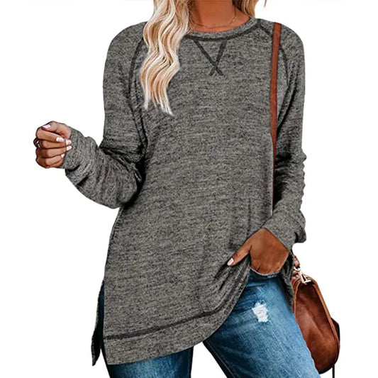 A woman wearing a grey solid color sweater with long sleeves, paired with ripped jeans and carrying a brown handbag.