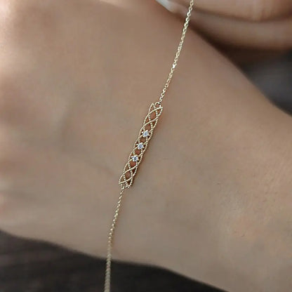 A sterling silver bracelet with gold plating, featuring a hollow pattern design, worn on a person's wrist.