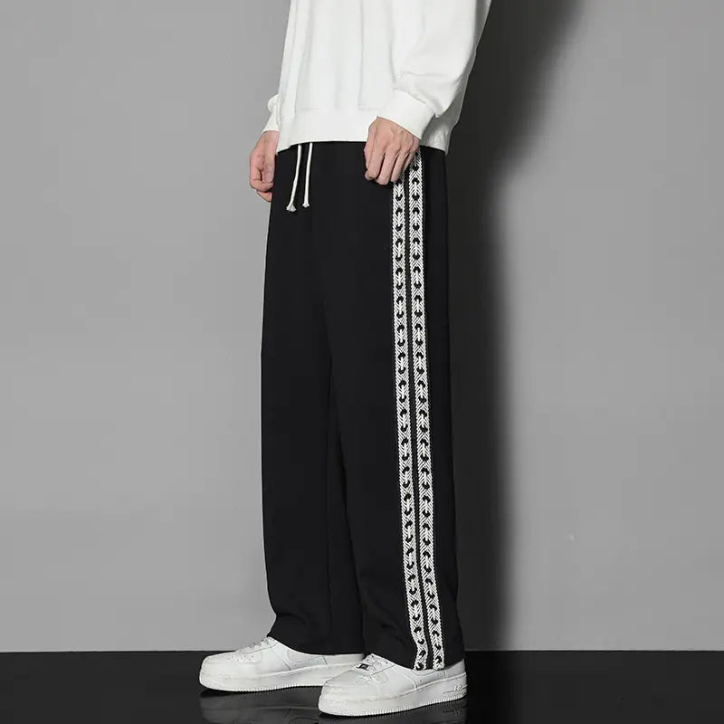 A person wearing black straight-leg casual exercise pants with a white drawstring waist and white decorative stripe details on the sides. The image has a 'Plus fleece thick' caption indicating the pants have additional lining for warmth.