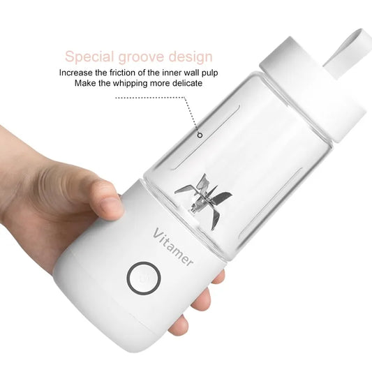 A white USB rechargeable blender with a clear container being held in a person's hand. The blender has a sleek design with a power button and a special groove around the inner wall.